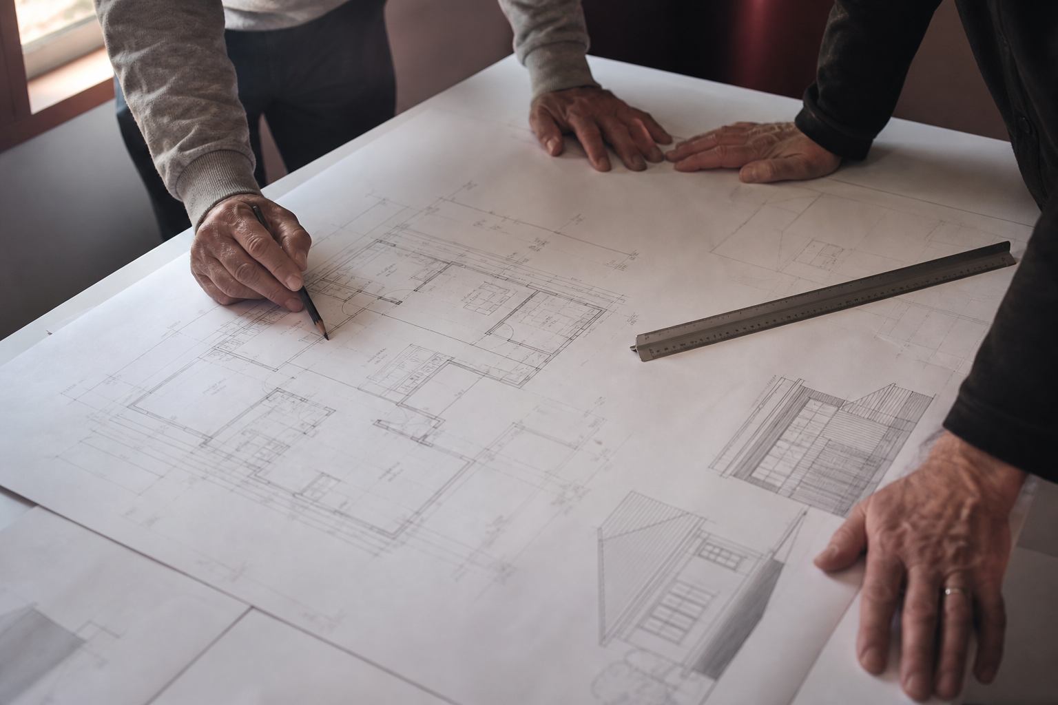 Architectural floor plans and elevations spread on a review table